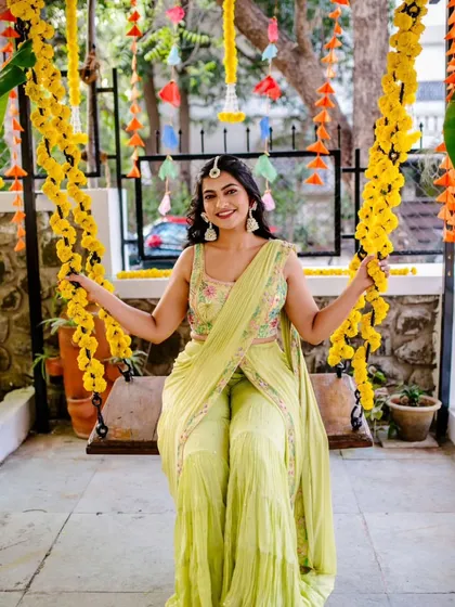A beautiful portrait of the bride during her Mehendi ceremony, seated on a swing adorned with marigolds, looking absolutely radiant.