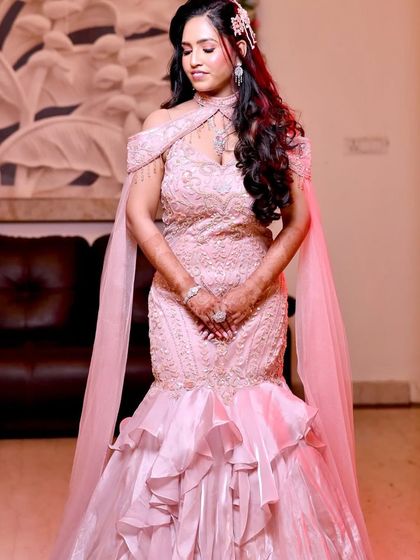 A full-length shot of Vijita's stunning pink engagement gown. The mermaid silhouette and ruffled train are perfectly complemented by her glamorous makeup.