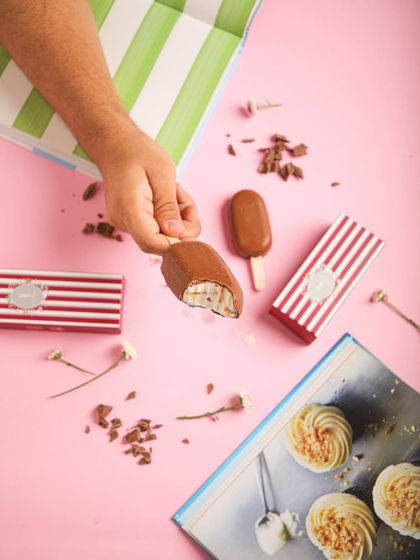 A hand reaches for one of our chocolate-coated ice cream bars. Unwrap the goodness!