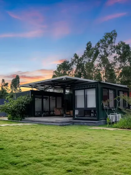 A wide view of the container office and its surrounding landscape at sunset. The image captures the project's serene setting and its successful integration of modern workspace design with nature.