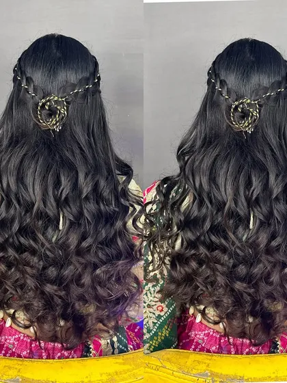 A still image of a half-updo with curls and a traditional hair accessory.
