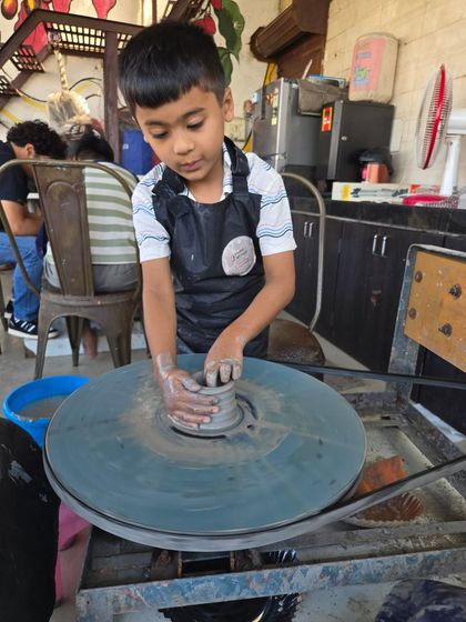 Learning the ropes of wheel throwing. This young boy is getting the hang of centering the clay, the first and most important step in pottery. I ensure every child gets one-on-one attention.
