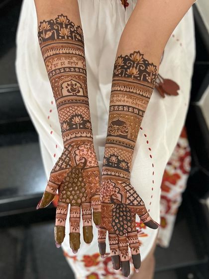 A full-coverage bridal design with personalized text, Ganesha, and peacock motifs.