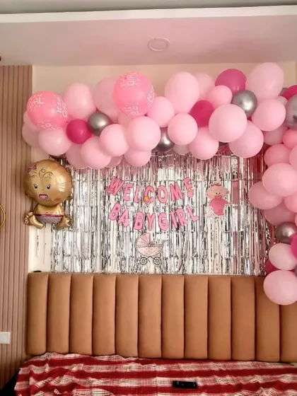 A lovely 'Welcome Baby Girl' decoration for a home. This setup is designed to fit perfectly over a bed, with a pink balloon garland and a silver shimmer curtain.