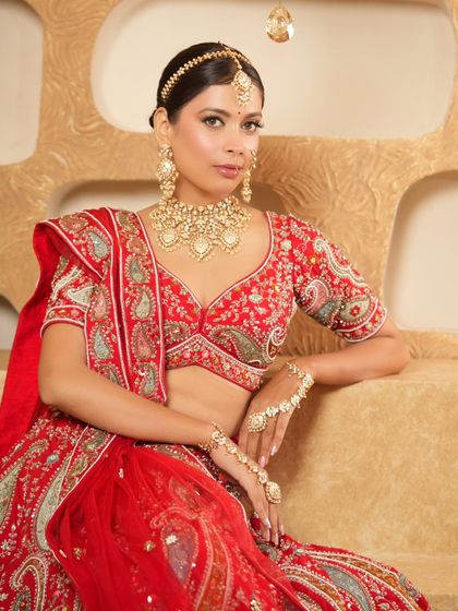 This classic red bridal lehenga with paisley motifs is paired with a stunning gold choker set. I ensure every detail of your rental look is perfectly coordinated.