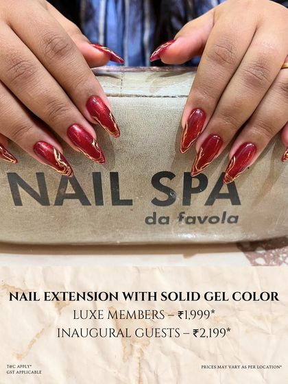 A stunning set of long, stiletto nail extensions in a deep, metallic red. The gold detailing along the edges adds a touch of luxury and drama to this show-stopping look.
