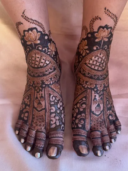 A heavy, intricate design for bridal feet, matching the divine-themed hand mehendi. The patterns are dense and filled with beautiful floral and geometric motifs.