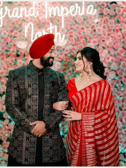 A joyful portrait of the couple against a wall of pink flowers. Their matching smiles and comfortable pose radiate happiness and the celebratory spirit of their engagement.