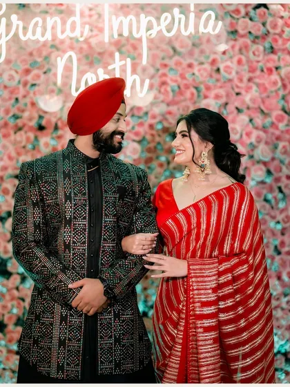 A beautiful shot of Vanaja and Angad against a wall of flowers, capturing a moment of shared laughter and joy.
