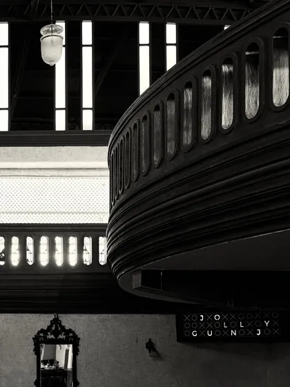 A composition showing the layers of the space: the mezzanine balcony, a vintage mirror below, and the tall windows in the background.