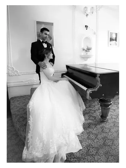 A sophisticated black and white portrait by the piano. This image showcases our ability to create elegant, classic pre-wedding pictures in an indoor setting, focusing on poise and connection.