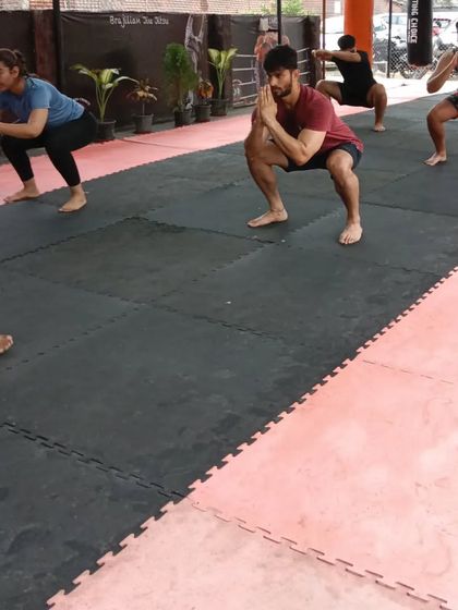 A group of members, men and women, perform squats together during a warm-up at our Sector 141 club. This synchronized effort builds a sense of unity and shared purpose in every session.