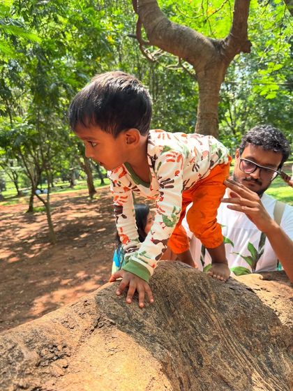 A father watches on, offering quiet support as his son navigates the tree. These moments of gentle encouragement are key to fostering a child's independence and courage.