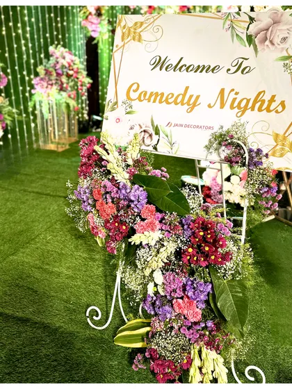 Even a comedy night deserves beautiful decor. A welcome sign is elegantly decorated with a cascade of colorful flowers, showing that every event, no matter the theme, can be stylish.