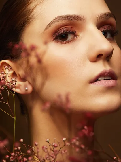 A soft, romantic look with a subtle smokey eye, framed by delicate baby's breath flowers. This showcases a more gentle and ethereal style of artistry.