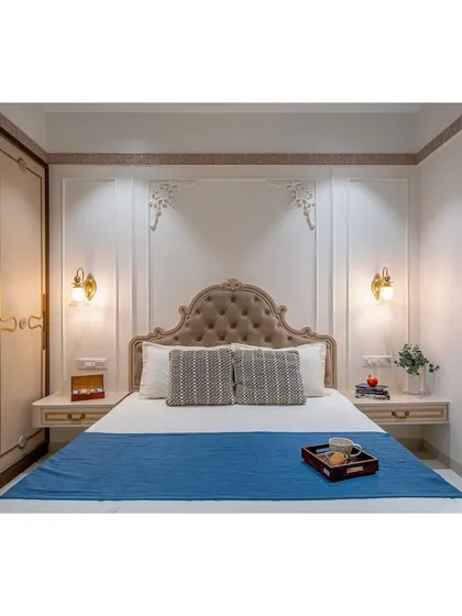 A full view of a Victorian-inspired master bedroom. The tufted headboard, ornate wall mouldings, and classic sconces create a timeless and elegant look.