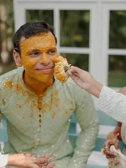 A friend playfully applying haldi to the groom. The ceremony is all about showering the couple with blessings and having fun.