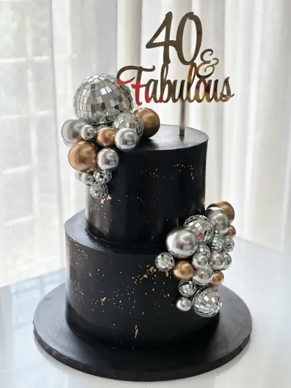 Forty and fabulous! This two-tiered black cake brings the party with shimmering disco balls and a cascade of silver and gold spheres, perfect for a glamorous celebration.