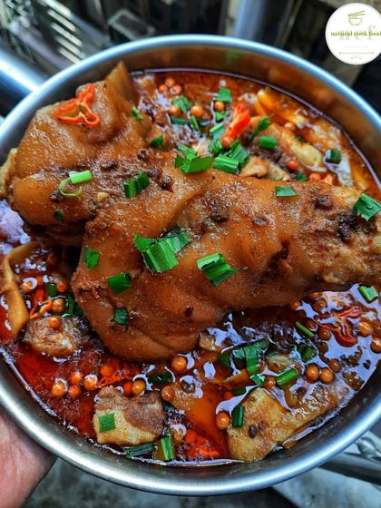 A giant pork leg cooked with fermented soybeans and bamboo shoots. It's garnished with fresh herbs and spicy king chilli, a special recipe I make for my team.