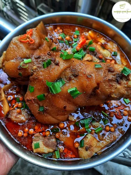 A giant pork leg cooked with fermented soybeans and bamboo shoots. It's garnished with fresh herbs and spicy king chilli, a special recipe I make for my team.