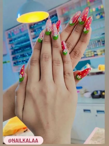 A fun and fruity strawberry-inspired design on long stiletto nails. The red tips and green leafy bases are hand-painted for a cute and unique look.