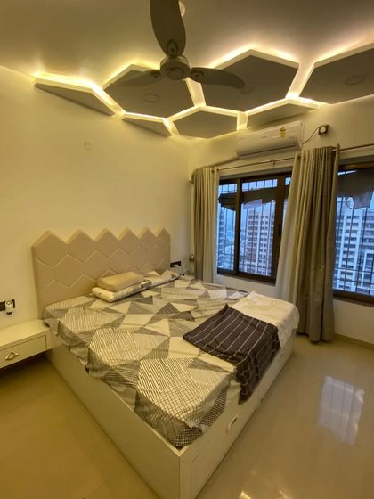 Another view of the hexagon-themed bedroom, showing the custom-designed headboard and the warm, ambient lighting from the false ceiling.