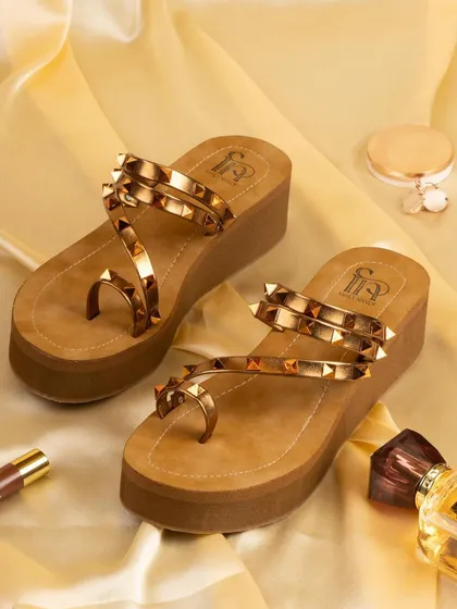 A pair of studded platform sandals for Fancy Nancy, styled on a golden silk background with perfume and makeup. This setup creates a glamorous, ready-for-a-night-out vibe.