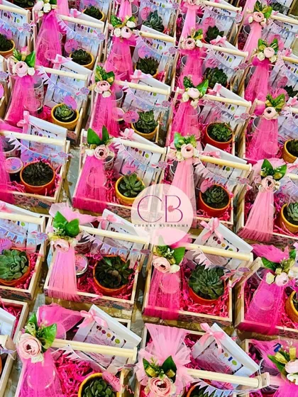 A sea of pink for a first birthday celebration. These luxurious candy-themed return favors are packed in decorated pinewood baskets, each containing a succulent plant and other sweet treats, all tied together with delicate floral arrangements.