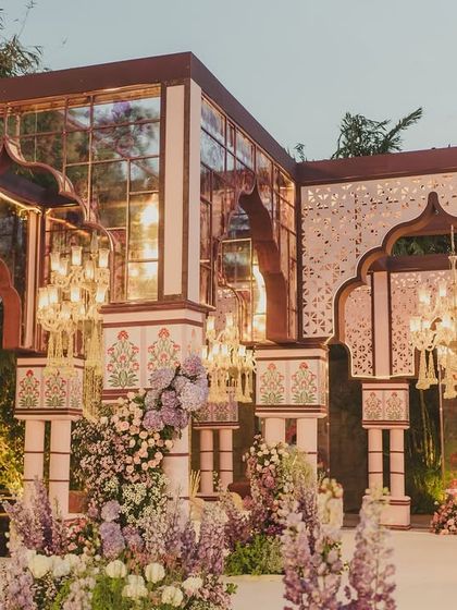 The wedding mandap was designed as a glasshouse structure with traditional arches and intricate jaali work, blending modern design with Rajasthani heritage.