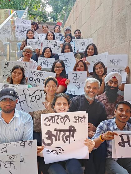 A happy group of calligraphy workshop participants posing on the stairs with their creations. Our workshops build a sense of community and shared accomplishment.