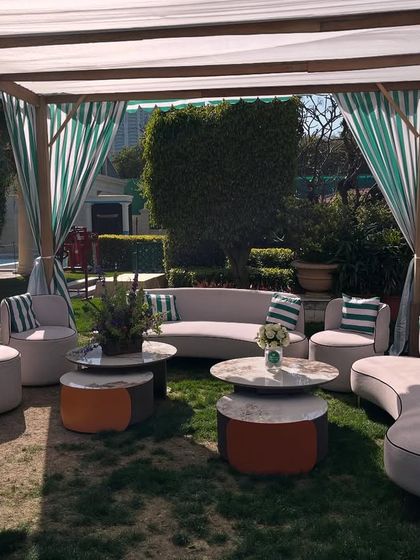 A closer look at the luxurious outdoor seating arrangement under a striped canopy. The curved sofas and plush cushions offer a comfortable and stylish space for guests.