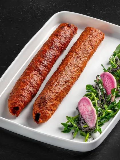 Seekh kebabs served with a fresh microgreen salad. The clean presentation highlights the texture and color of the kebabs.