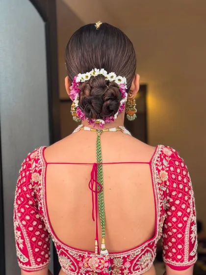 The back view of a classic floral bun, showing the neat wrap and the beautiful arrangement of fresh flowers. This is a popular choice for brides wanting a traditional yet fresh look.