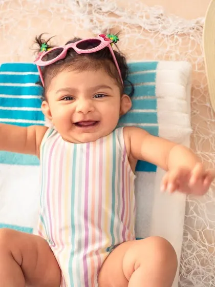 A big, happy grin from our little beach baby. Her tiny sunglasses and joyful expression are what summer dreams are made of.