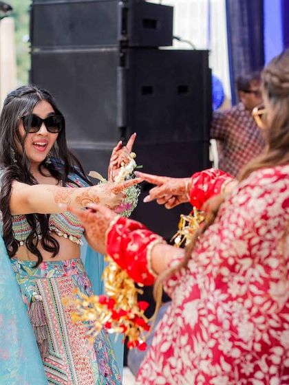 A fun, candid moment between two friends during a mehendi dance performance.
