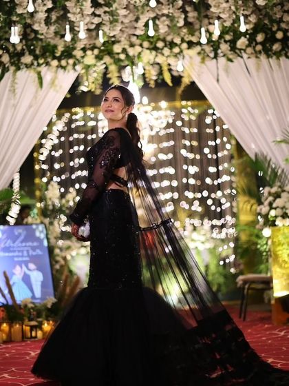 A stunning full-length shot against a backdrop of fairy lights. The mermaid-style gown with a long train is pure drama and elegance for a reception or cocktail party.