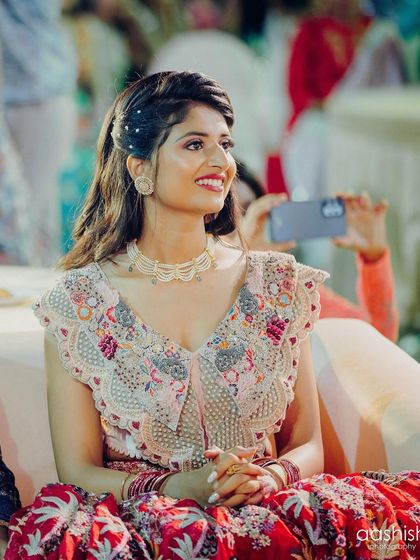 A happy, seated portrait of the bride. Her makeup is fresh and radiant, and the pearl details in her hair add a touch of elegance.