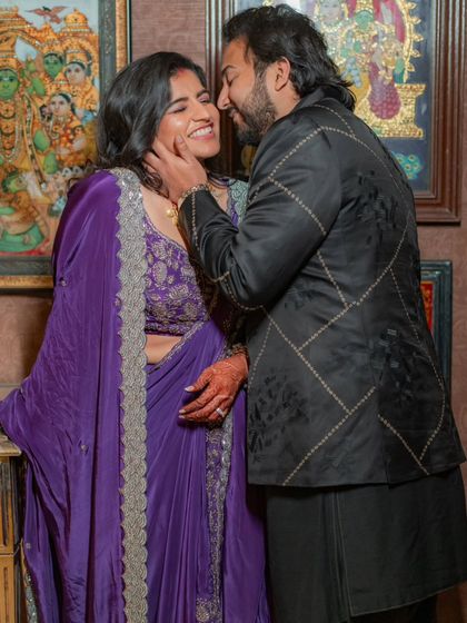 An intimate moment between the couple. This photo gives a closer look at the custom purple reception outfit, showing the detailed embroidery on the blouse and the elegant drape of the saree-style gown.