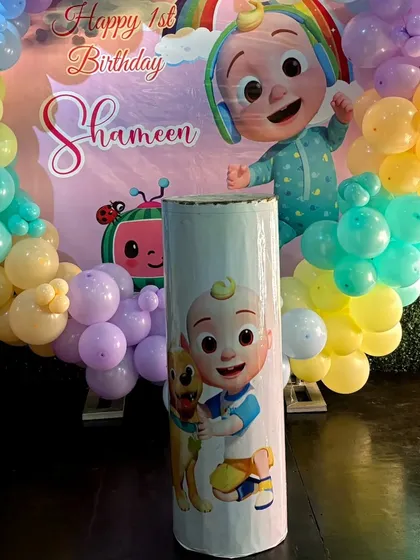 This themed pedestal, featuring a Cocomelon character, is perfect for holding a cake or other party elements.