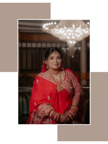 A classic portrait of Shalini, her red saree and gold jewelry standing out against the backdrop of a grand chandelier.