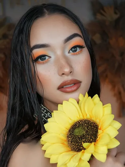 A bold and creative look inspired by a sunflower. The bright orange eyeshadow and wet-look hair create a fierce and artistic vibe.