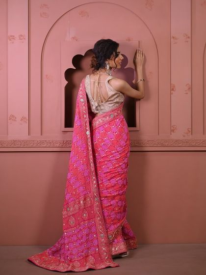 The back view of a stunning pink bandhani saree, paired with a golden blouse. The intricate weave and vibrant color create a captivating look.