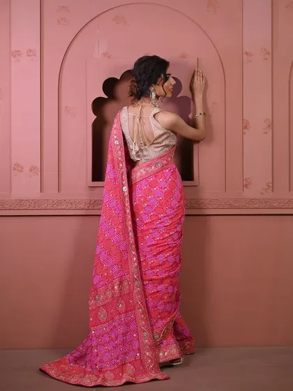 The back view of a stunning pink bandhani saree, paired with a golden blouse. The intricate weave and vibrant color create a captivating look.