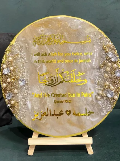 I love creating pieces that celebrate life's most precious moments. This is a custom engagement plaque featuring the Quranic verse 'And We Created You In Pairs', personalized with the couple's names. It's finished with a marble effect resin, pearls, and crystals.