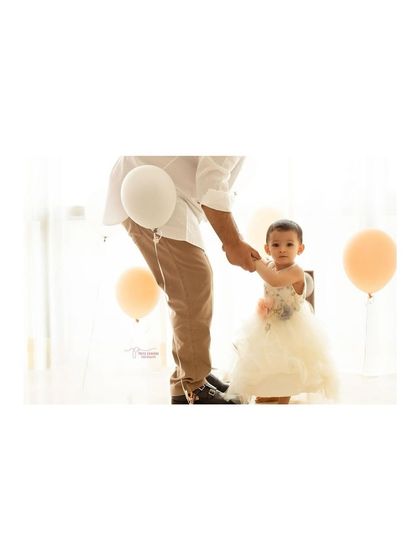 A father's guiding hand as his daughter takes a step on her first birthday. These are the small, significant moments we capture during a milestone session.
