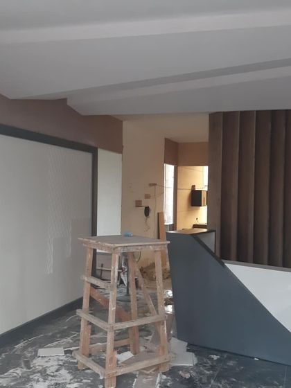 An office reception area during the finishing stages. The wall paneling, reception desk structure, and fluted details are in place, awaiting the final touches that will bring the design to life.
