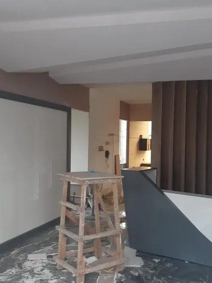 An office reception area during the finishing stages. The wall paneling, reception desk structure, and fluted details are in place, awaiting the final touches that will bring the design to life.