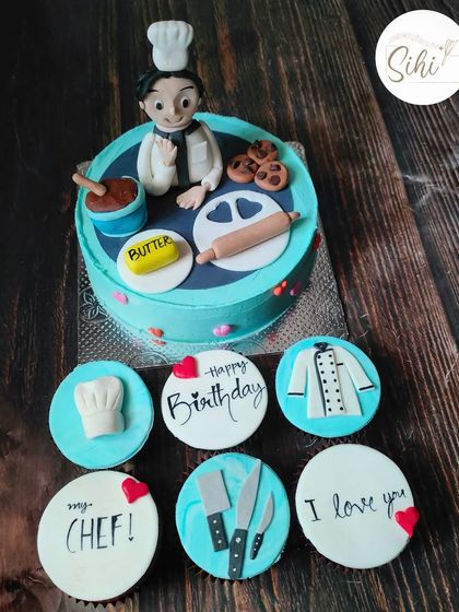 "Yes, Chef." A cake and cupcake set for a chef's birthday. The design includes a fondant chef figurine and toppers shaped like knives, a chef's coat, and other kitchen essentials.