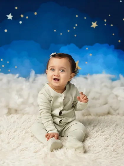 This little girl is sitting up proudly during her sitter session, set against a dreamy 'twinkle twinkle little star' backdrop. This stage is perfect for capturing their budding personality.