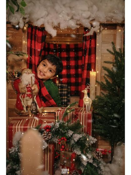 A sweet portrait of the boy peeking out of the cabin window with a Santa figurine.